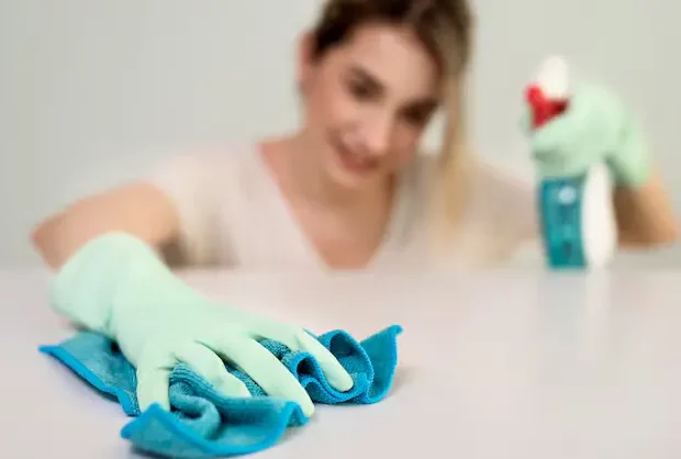 Professional cleaner vacuuming and dusting living room