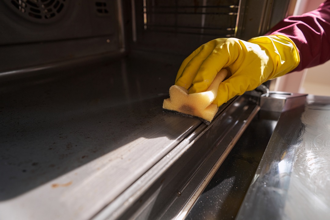 Technician deep cleaning a kitchen oven in Essex with non-toxic products